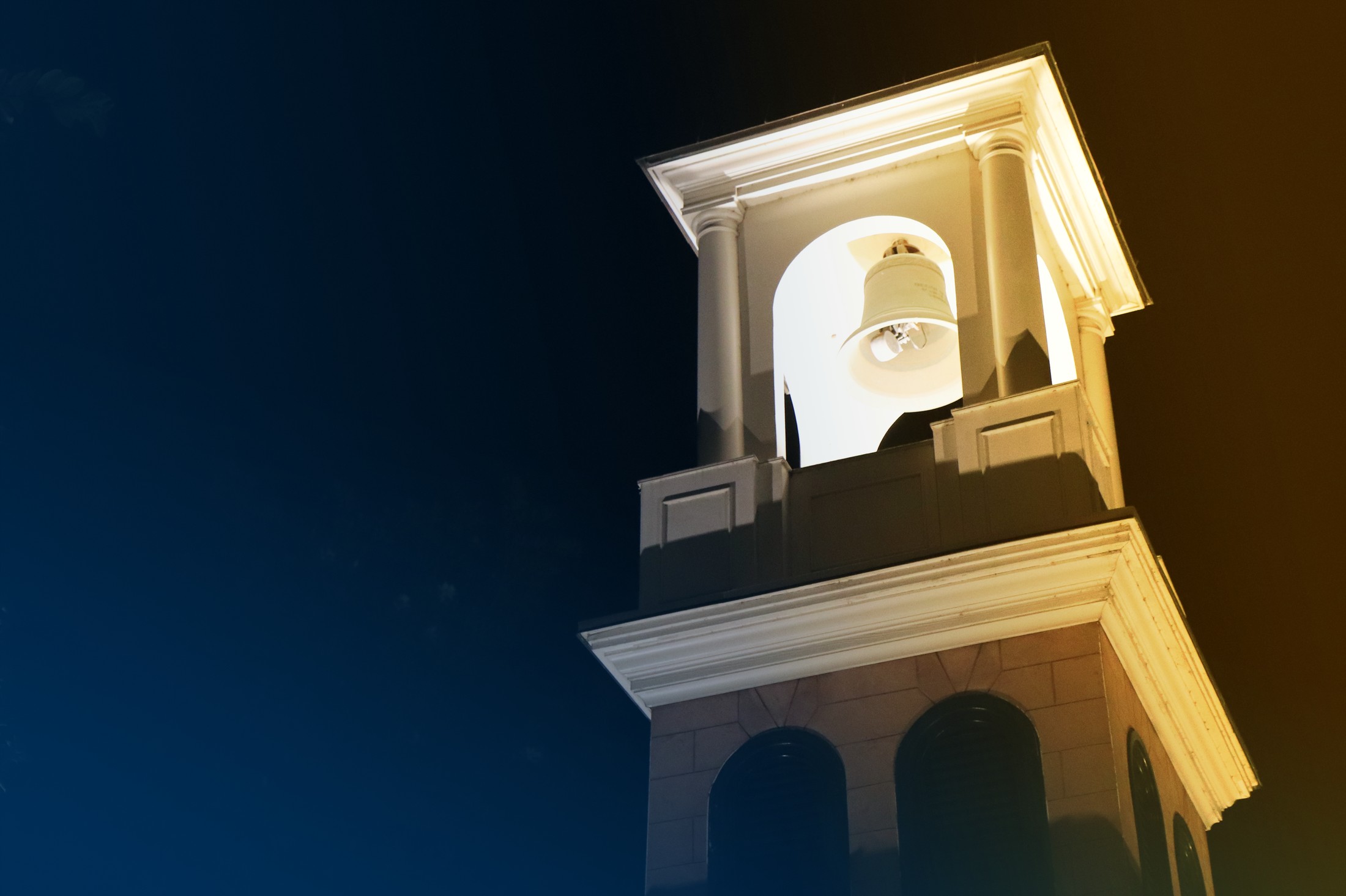 Illuminated bell tower against a dark blue night sky